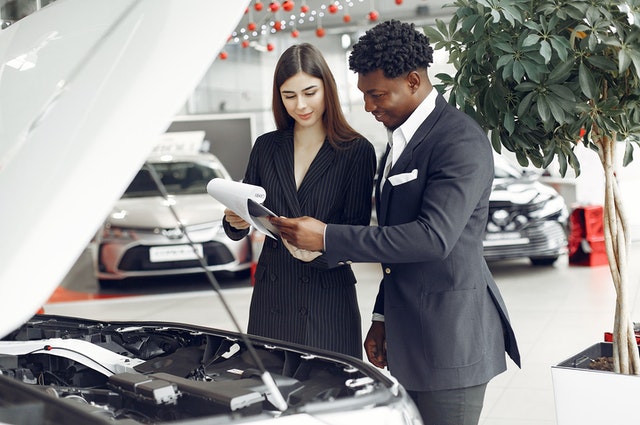 saleswoman with man looking at engine bay - Buying a Home with Tax Liens Benefits