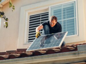 Man with Gloves Holding Solar Panels on the Roof 300x225 - Man with Gloves Holding Solar Panels on the Roof