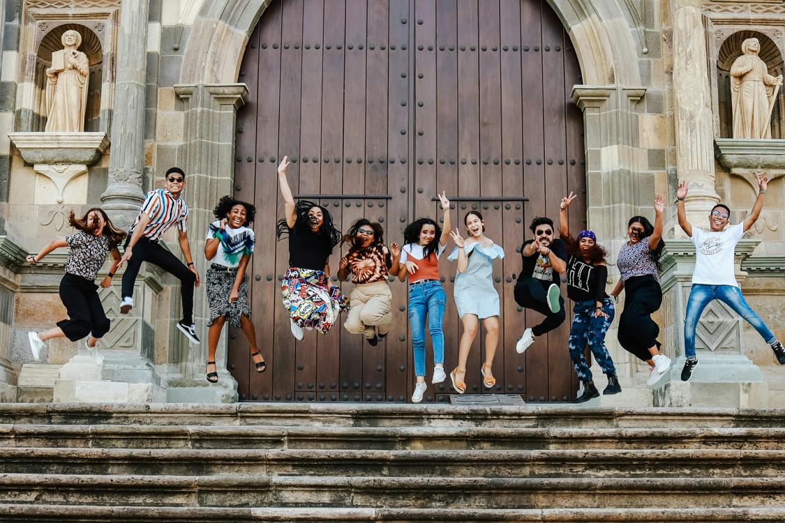 group of young people jumping in the air at the church steps - Partnering with Churches for Impactful Youth Group Trips