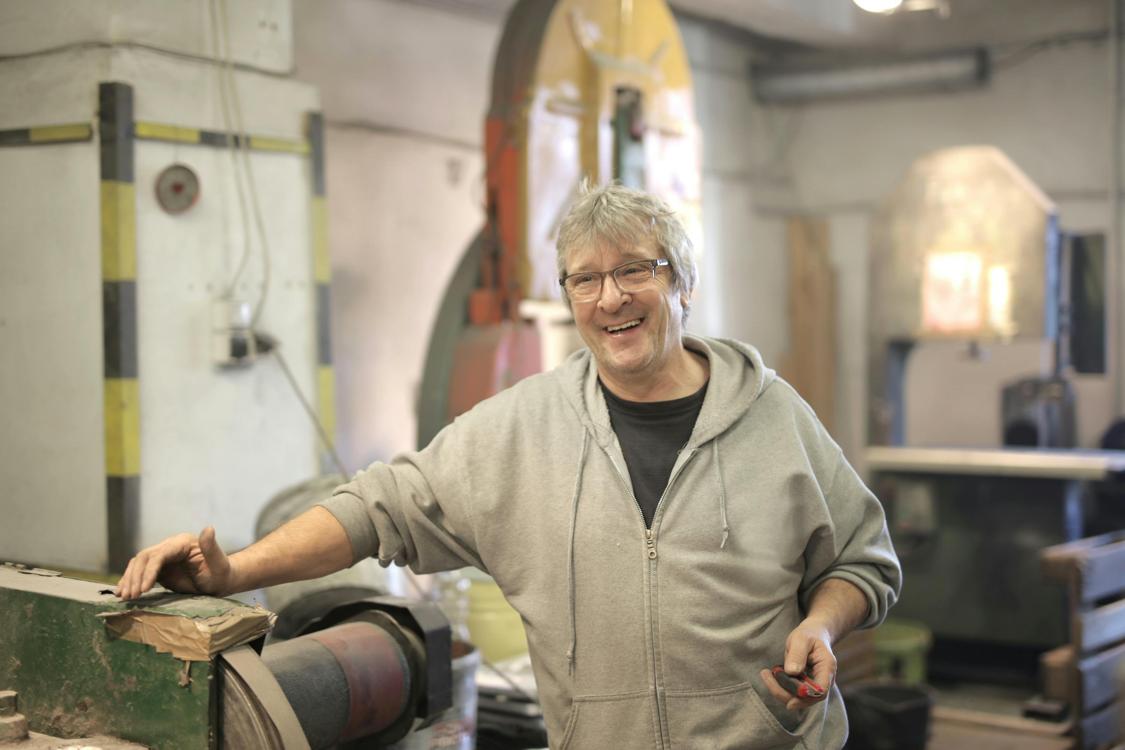 happy elderly worker smiling in workshop - Picking a Plastic Injection Molding Company for Your Project