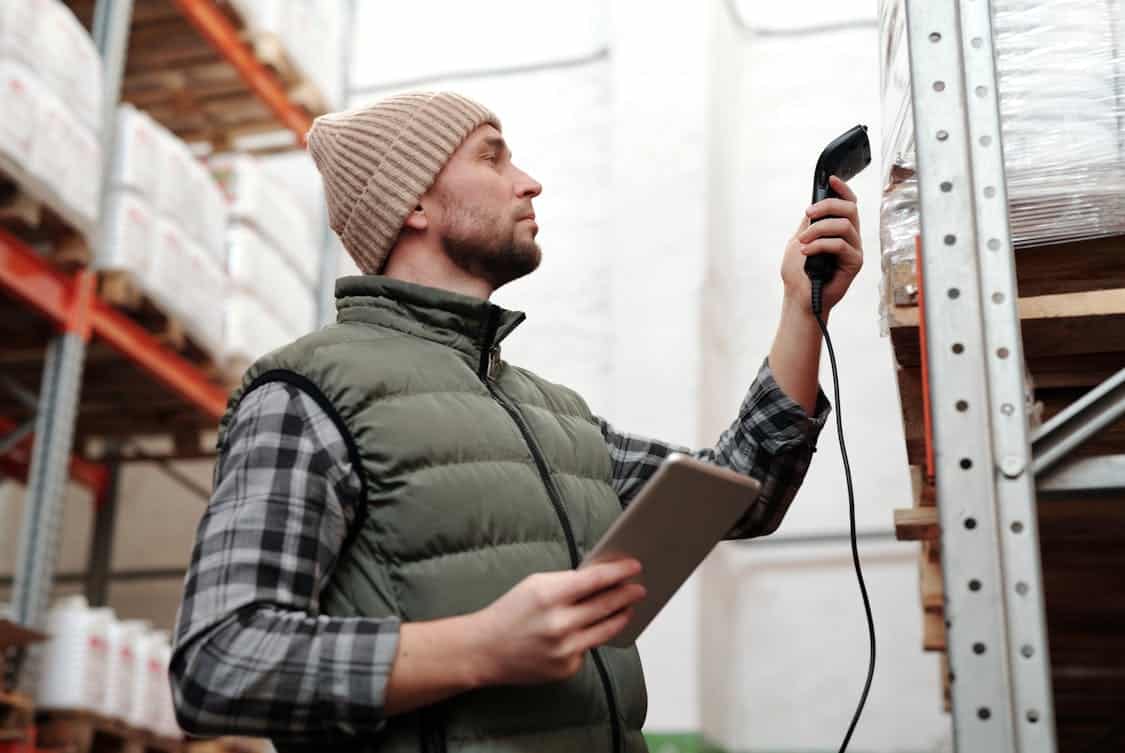 Photo of a Man Scanning Products in a Warehouse - How Staffing Agencies Help During Seasonal Hiring Rush