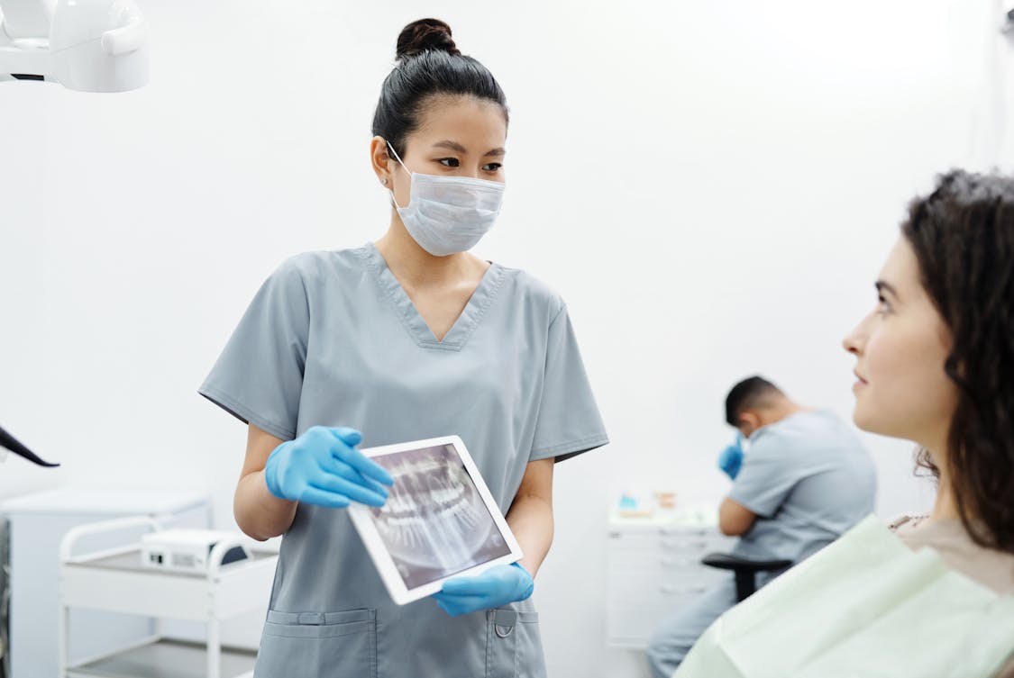 A Woman Showing the X ray of Teeth to a patient - Digital Transformation Strategies for Growing Dental Networks