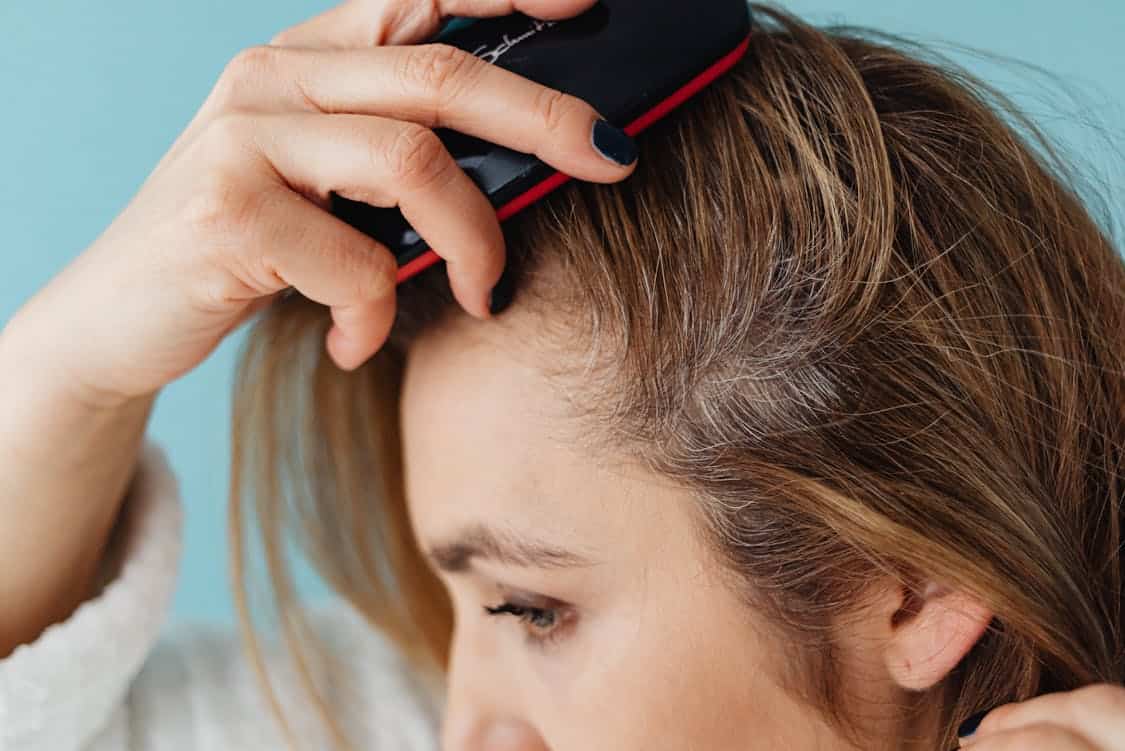 A Close up Shot of a Woman Brushing Her Hair - How Hair Growth Spray Works With Thinning Hair Types