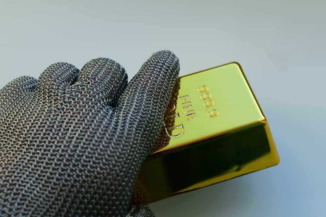 hand holding a gold bar - Why Precious Metals Remain the Ultimate Safe Haven Asset