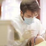 Dentist in face mask conducting a dental examination 150x150 - Home