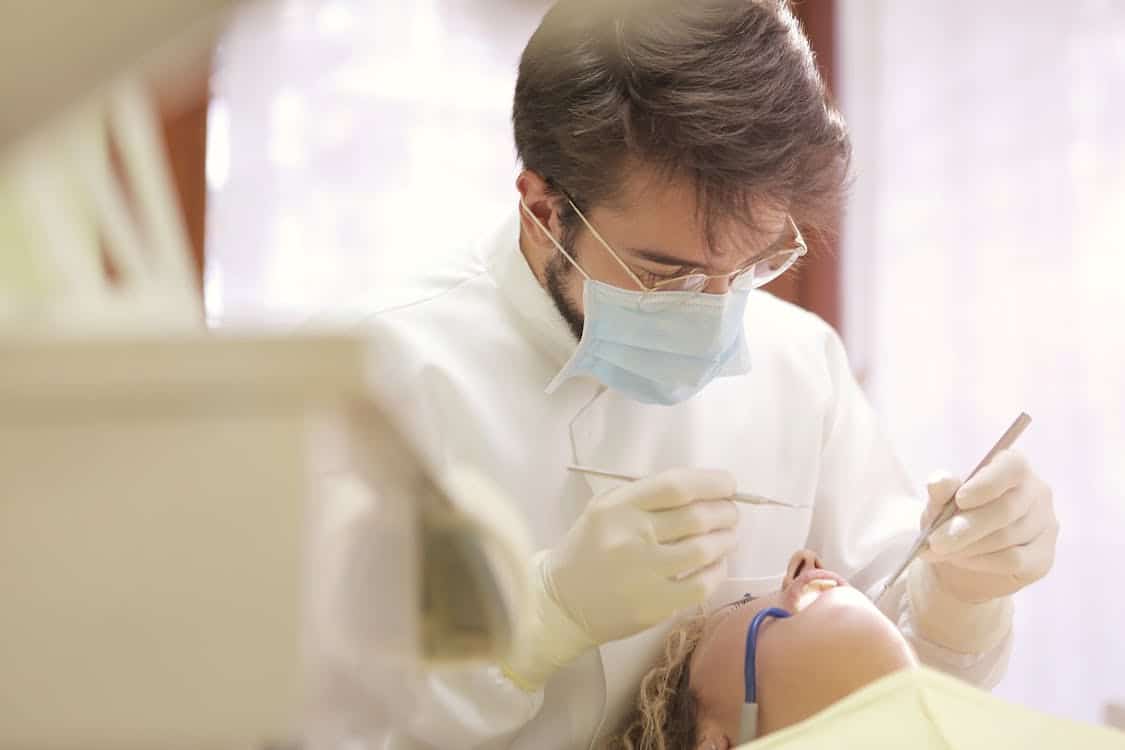 Dentist in face mask conducting a dental examination - Hays County's Population Surge Is Straining the Dental Care Infrastructure Already There