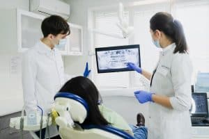 Two dentists examine a dental X ray with a patient 300x200 - Two dentists examine a dental X-ray with a patient