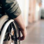 close up of a person in a wheelchair is navigating an indoor hallway 150x150 - Home