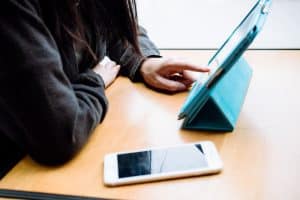 a woman tapping screen of a tablet on a wooden table 300x200 - a woman tapping screen of a tablet on a wooden table