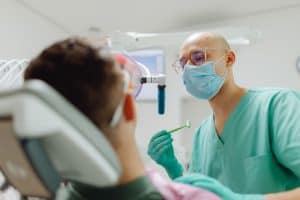 Dentist examining a patients teeth with 300x200 - Dentist examining a patient's teeth with